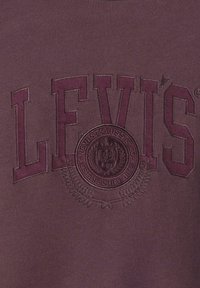 Bordowy sweter z haftowanym logo "LEVI'S", okrągłym emblematem z detalami oraz gładkim, teksturowanym wykończeniem tkaniny.