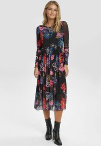 Svart blommig klänning med långa genomskinliga ärmar, med färgglada blommor i rosa, blått och lila; lagerkjol och subtil textur.