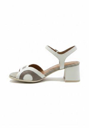 Białe i beżowe sandały damskie z odkrytym palcem, na słupku z paskiem wokół kostki, z zakrzywionym wzorem color-block na przodzie.