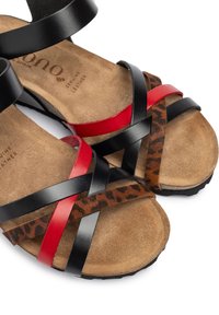Sandali in pelle nera, rossa e con stampa animale con soletta in camoscio; le cinghie regolabili si incrociano sul piede per supporto e stile.