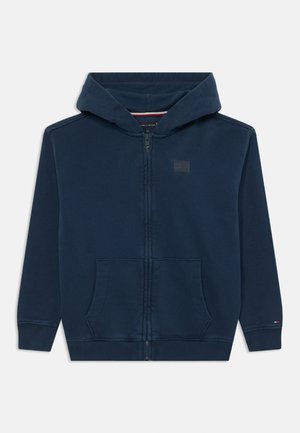 Mørkeblå zip-up hættetrøje med snor i hætten, to forlommer, ribbede manchetter og et lille firkantet logo på brystet. Con-blandingsstof.