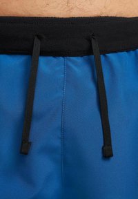 Pantalones cortos de baño azules con una textura suave, que presentan una cinturilla elástica negra y dos cordones negros para ajuste.