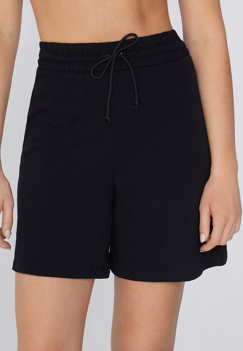 Zwarte katoenen shorts met een elastische tailleband en een trekkoord, met een relaxte pasvorm en een gladde textuur. Geen zichtbare zakken.