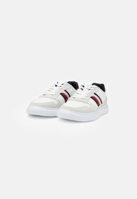 Sneaker bianche con materiali in suede e rete, caratterizzate da strisce rosse e blu navy sui lati, suole in gomma bianca e design con lacci.