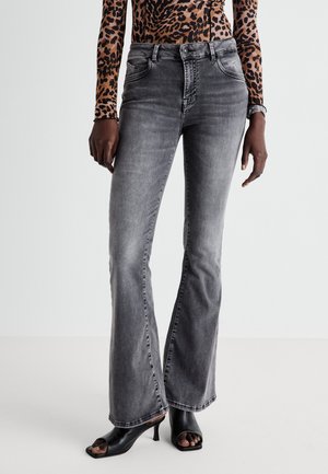Grey flared jeans made of denim, featuring five pockets, medium wash, and subtle fading, paired with black open-toed heels.