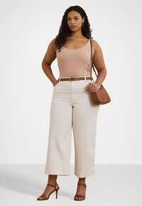 Ljusrosa ärmlös topp, beiga högmidjade vida byxor, brunt läderbälte och matchande handväska. Bruna remsandaler med hög klack.