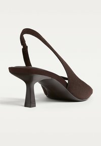 Bruna mockaskinn slingback-klackar med spetsig tå och en smal, något utsvängd klack, med en slät yta och minimalistisk design.