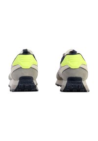 Sneaker con una parte superiore crema e grigia, accenti giallo neon e una suola grigia testurizzata. Design chunky con schienale imbottito e dettaglio del logo.