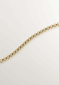 Pulsera de cadena de metal dorado con eslabones ovalados entrelazados, textura suave y acabado pulido, colocada sobre un fondo claro.