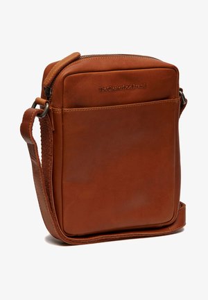 Bruine lederen schoudertas met een vierkante vorm, ritssluiting en verstelbare schouderriem. De tas heeft een reliëflogo aan de voorkant en een gladde textuur.