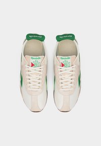 Ζευγάρι λευκών και μπεζ αθλητικών παπουτσιών Reebok με πράσινες λεπτομέρειες, κορδόνια δεμένα, εμφανιζόμενα από πάνω σε λευκό φόντο.
