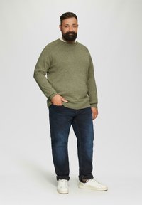 Olijfgroen gestructureerd sweater, relaxte pasvorm, ronde hals, gecombineerd met donkerblauwe jeans en witte sneakers. Eenvoudig ontwerp, casual look.