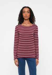 Bordeaux langærmet skjorte med hvide vandrette striber, der har en bred halsudskæring og blødt stof, parret med blå jeans.