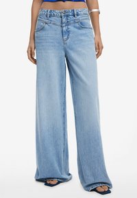 Wide-leg light blue jeans made of denim, featuring a high waist, front pockets, and a subtle faded texture.