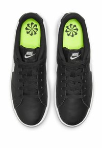 Sapatilhas Nike pretas com um upper de couro liso, detalhes brancos, atacadores pretos e uma palmilha verde néon com um padrão floral preto.