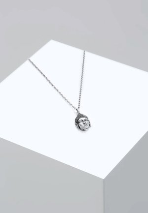 Collana argento con pendente a testa di Buddha, caratterizzata da espressioni facciali dettagliate e capelli texturizzati, su una catena sottile, esposta su uno sfondo chiaro.