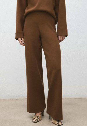 Pantalons larges marron en tissu doux, avec une taille haute et une coupe décontractée. Associés à des talons imprimés serpent.
