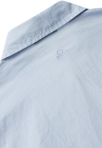 Camicia col collare azzurro chiaro sul retro con un sottile logo del marchio ricamato vicino al centro superiore sotto il colletto.