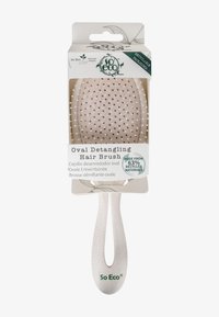 Ovale Entwirrbürste für Haare mit einem weißen Kunststoffgriff und flexiblen Borsten. Verpackt in recycelbaren Materialien, gekennzeichnet mit umweltfreundlichen Details.