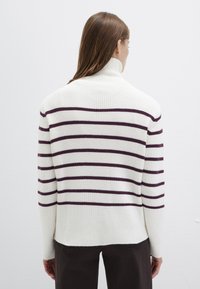 Gestreifter Pullover in Weiß mit dunkelvioletten horizontalen Streifen, mit hohem Kragen und geripptem Textur, von hinten gezeigt.
