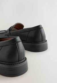 Sorte læder loafers med en tekstureret overflade, afrundede tæer og en polstret indersål. Sålen er lagdelt med en glat finish.