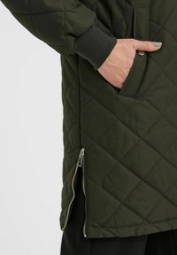 Giacca imbottita di colore verde scuro, con polsini a coste e una tasca laterale con zip, caratterizzata da una texture liscia e un motivo a diamante.