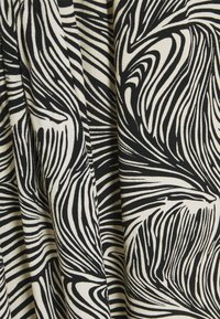 Černobílá tkanina s vířivými, abstraktními vzory. Materiál má texturovaný vzhled s plynulými liniemi a proměnlivou šířkou vzoru.