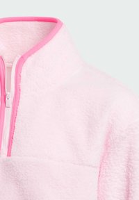 Pull en polaire rose clair avec un col haut, doté d'une fermeture éclair rose et d'un tissu à texture lisse. Détails de couture minimal.