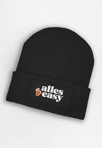 Black knitted beanie with a folded cuff. Features a rectangular patch with white text "alles easy" and an orange hand gesture graphic.