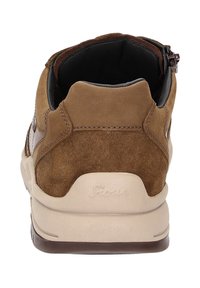 Baskets en daim marron avec une semelle en caoutchouc beige, présentant une texture lisse, un col rembourré et un logo de marque visible sur le talon.