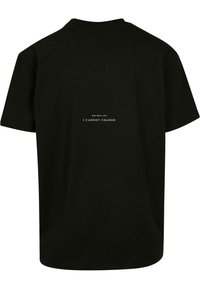Juodas medvilnės T-shirt'as su trumpomis rankovėmis, su apvaliu kaklu ir balta užrašu ant nugaros, kuris sako "ŠIAM GYVENIMUI AŠ NEGALIU PASIKEISTI."