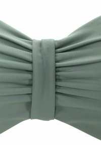 Fiocco in tessuto verde con una texture plissettata e una fascia centrale liscia. Il materiale appare morbido ed elastico con una leggera lucentezza.