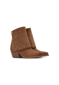 Botas de ante marrón hasta el tobillo con punta afilada y tacón de cuña. Presentan detalles con tachuelas a lo largo del cuello y en la parte delantera.