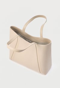 Μπεζ δερμάτινη τσάντα tote με δύο λουριά ώμου και ελαφρώς υφασμένη επιφάνεια, εμφανίζεται άδεια σε απλό λευκό φόντο.
