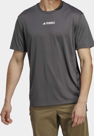 Camiseta deportiva gris de manga corta hecha de tela que absorbe la humedad, con un logo blanco "TERREX" en el pecho. Textura suave, ajuste relajado.