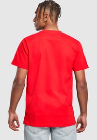Camiseta de algodón roja con mangas cortas, cuello redondo y un ajuste relajado. La tela parece suave, con un color sólido y sin patrones visibles.