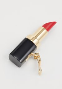 Labial rojo en un tubo negro y dorado, con una forma cuadrada elegante, un acento de hoja dorada y una punta afilada para una aplicación precisa.