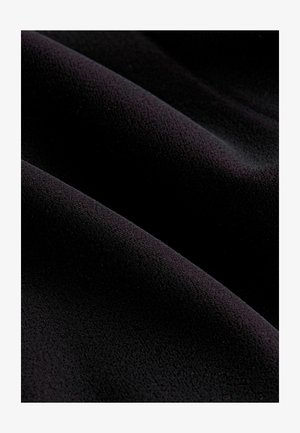 Black fabric with a smooth, textured surface, featuring gentle waves and folds. Material appears soft and plush.