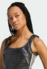 Czarny top na ramiączkach z wzorem krokodyla, szerokimi paskami i trzema białymi pionowymi paskami po boku, prezentujący elegancki, teksturowany design.