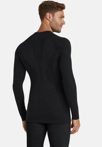 Zwarte sportshirt met lange mouwen, voorzien van een textuurgebonden patroon op de rug en een gladde stof, ontworpen voor een optimale pasvorm en comfort.