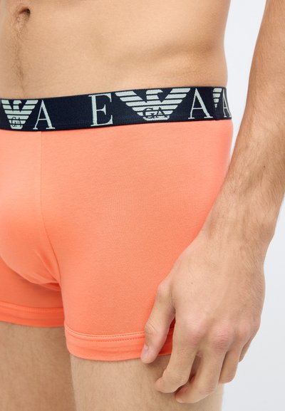 Boxer de algodão laranja com cós azul-marinho e logótipo com as letras "EA". Textura suave, ajuste justo e detalhes de bainha costurada.