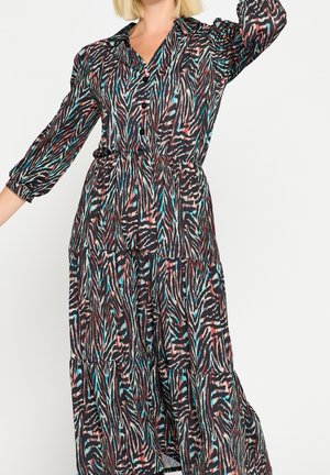 Kvinde iført en langærmet, knaplukket, flerfarvet kjole med zebra print, med krave og indsnævret talje.