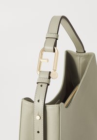 Borsa a tracolla verde in pelle con forma strutturata, tracolla regolabile e hardware dorato. Presenta una tasca con zip e una texture liscia.