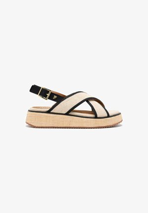 Sandalia de lona beige con acentos negros y hebilla ajustable, que cuenta con una suela de plataforma texturizada para agarre y soporte.