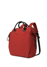 Sac à dos rouge avec poignées et bretelles noires, poche avant zippée et détail côté noué, présenté en angle sur fond blanc.