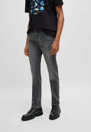 Grå denim jeans med slim fit, subtilt slid, fem-lomme design og bæltestropper i taljen, parret med sorte snørebåndsstøvler.