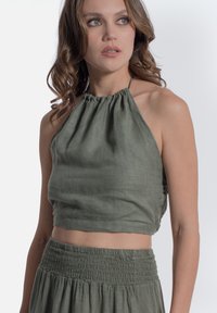 Top verde a fascia realizzato in tessuto leggero con scollatura arricciata, abbinato a una gonna con vita arricciata, creando un completo coordinato.
