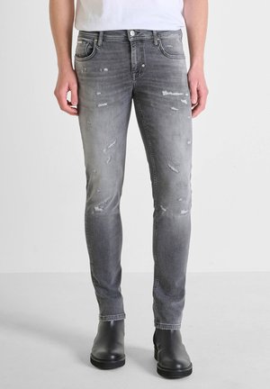 Gray denim jeans with distressed areas, slim fit, five-pocket design, and a faded effect; paired with black ankle boots.