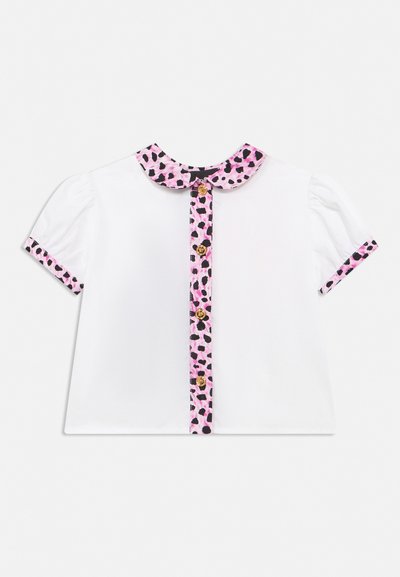 Λευκό μπλουζάκι με κοντά μανίκια και φουσκωτά μανίκια, με ροζ και μαύρο λεοπάρ μοτίβο στο γιακά, τις μανσέτες και το πατιλέτα με χρυσά κουμπιά.
