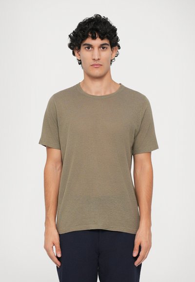 Olijfgroen t-shirt met korte mouwen, gemaakt van een zachte, textuurstof met een ronde halslijn en een rechte zoom. Draagt met donkere broeken.